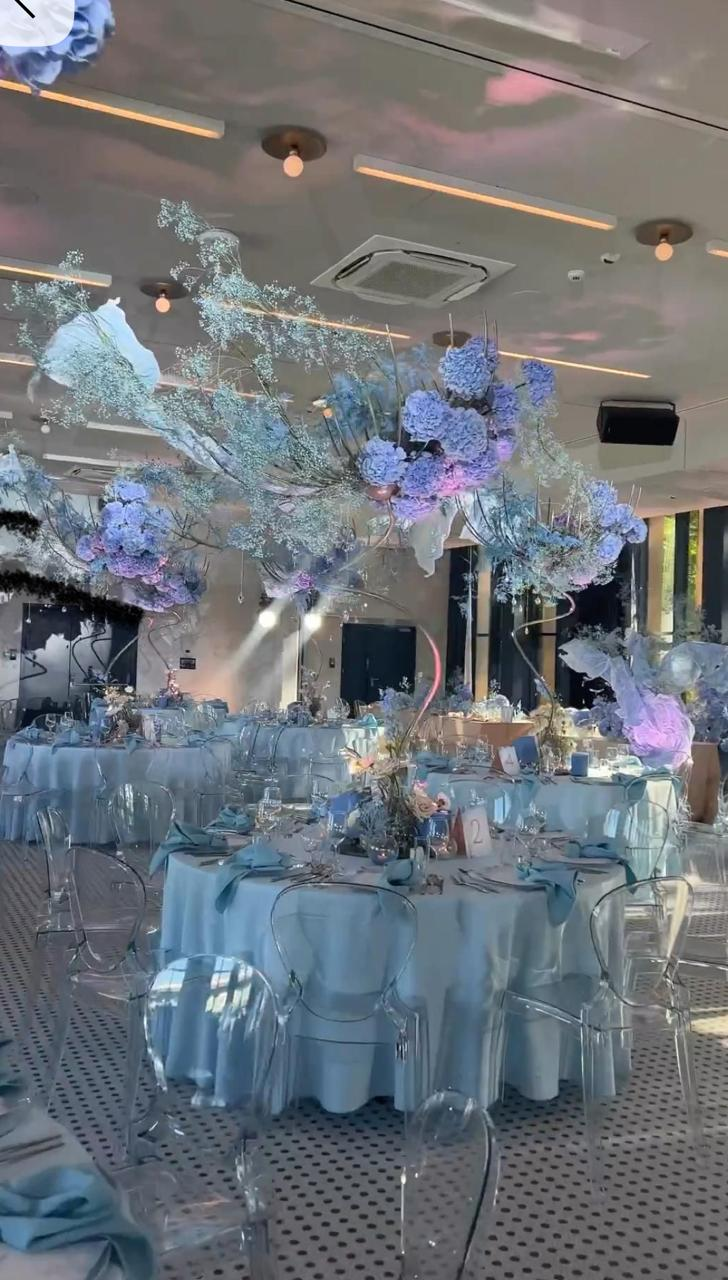 Powder-blue luxury wedding tablescape with hanging hydrangea installation, ghost chairs and crystal glassware by Shaddai Brands
